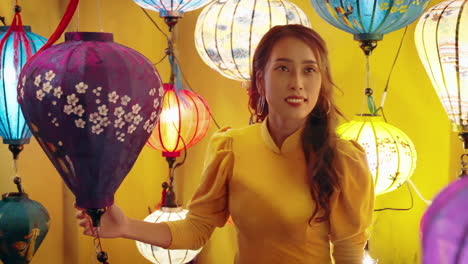 woman in yellow ao dai admiring lanterns in hoi an, vibrant colors