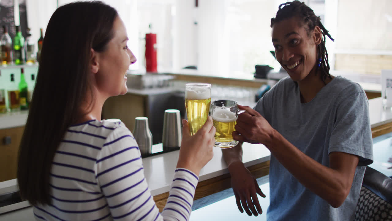 un grupo diverso de amigos felices bebiendo cervezas y hablando en un bar