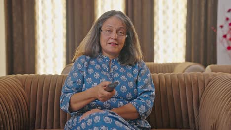 happy indian aged woman watching tv