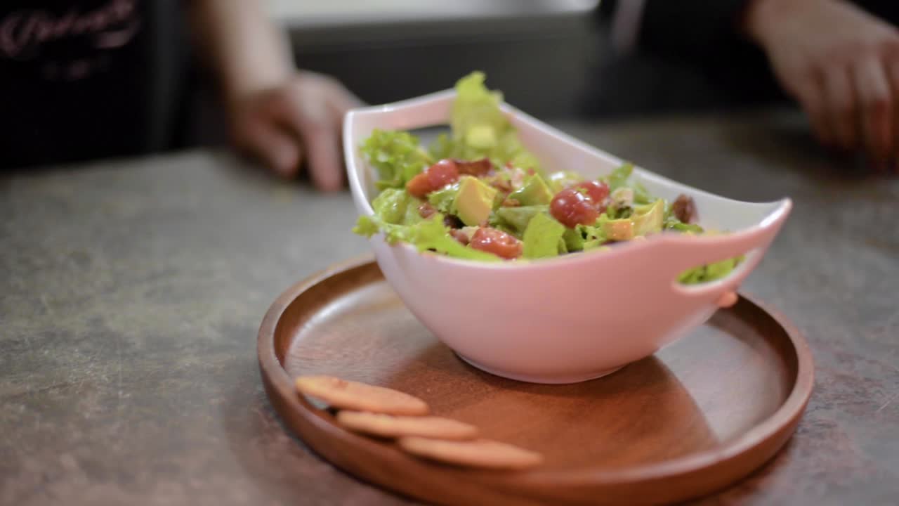 Woman chef cook preparing a salad adding slices of avocado at a local restaurant diner cafe in Mexico latin america