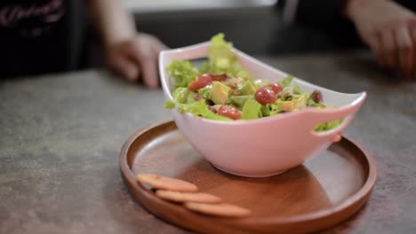 woman chef cook preparing a salad adding slices of avocado at a local restaurant diner cafe in mexico latin america