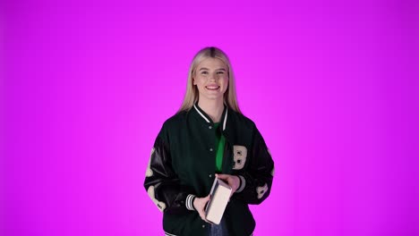 smart young female college student reads a large book, smiling, studio shot
