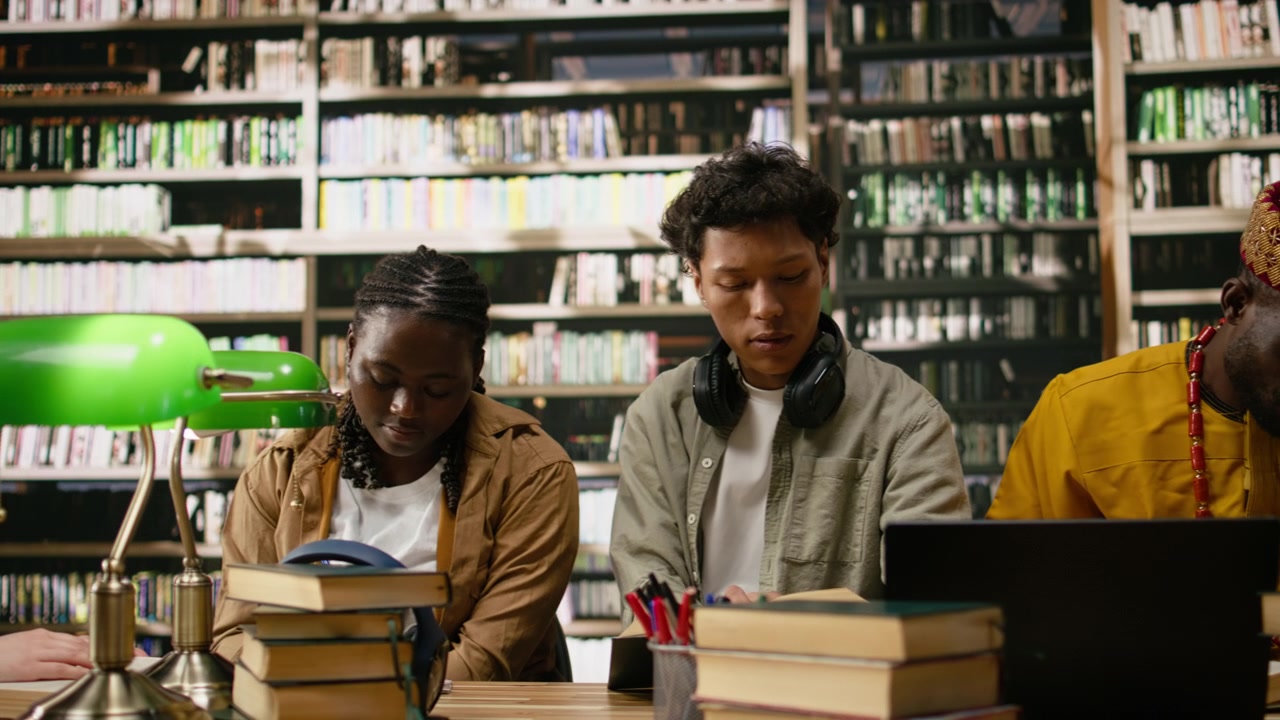 Students working around laptop and open books during library study session