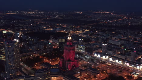 Aerial-panoramic-footage-of-large-city-at-night.-Palace-of-Culture-and-Science-illuminated-by-red-light.-Warsaw,-Poland