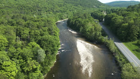 Panoramic-view-of-shallow-West-River-in-between-lush-foliage-in-West-Dummerston,-Vermont--aerial-drone-shot