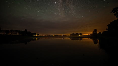 lapso de tiempo de la puesta de sol sobre un lago con estrellas que aparecen en el cielo