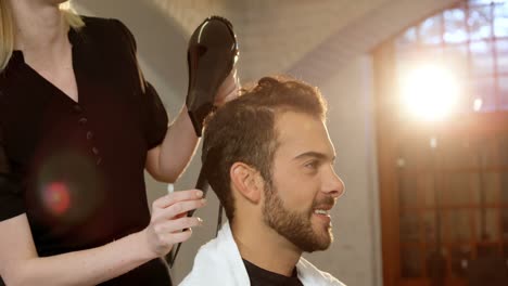 hombre sonriente secándose el cabello con un secador de pelo