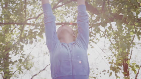 woman outdoors in fitness clothing stretching arms and celebrating nature