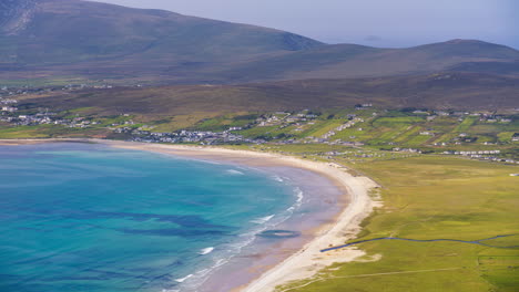 timelapse of seaside village grass and lake hillside landscape with local sand beach and clouds casting shadows in daylight viewed from minaugn heights in achill island in county mayo in ireland