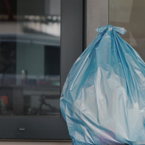 Man-Puts-A-Bag-Of-Household-Rubbish-On-The-Doorstep-Of-The-House