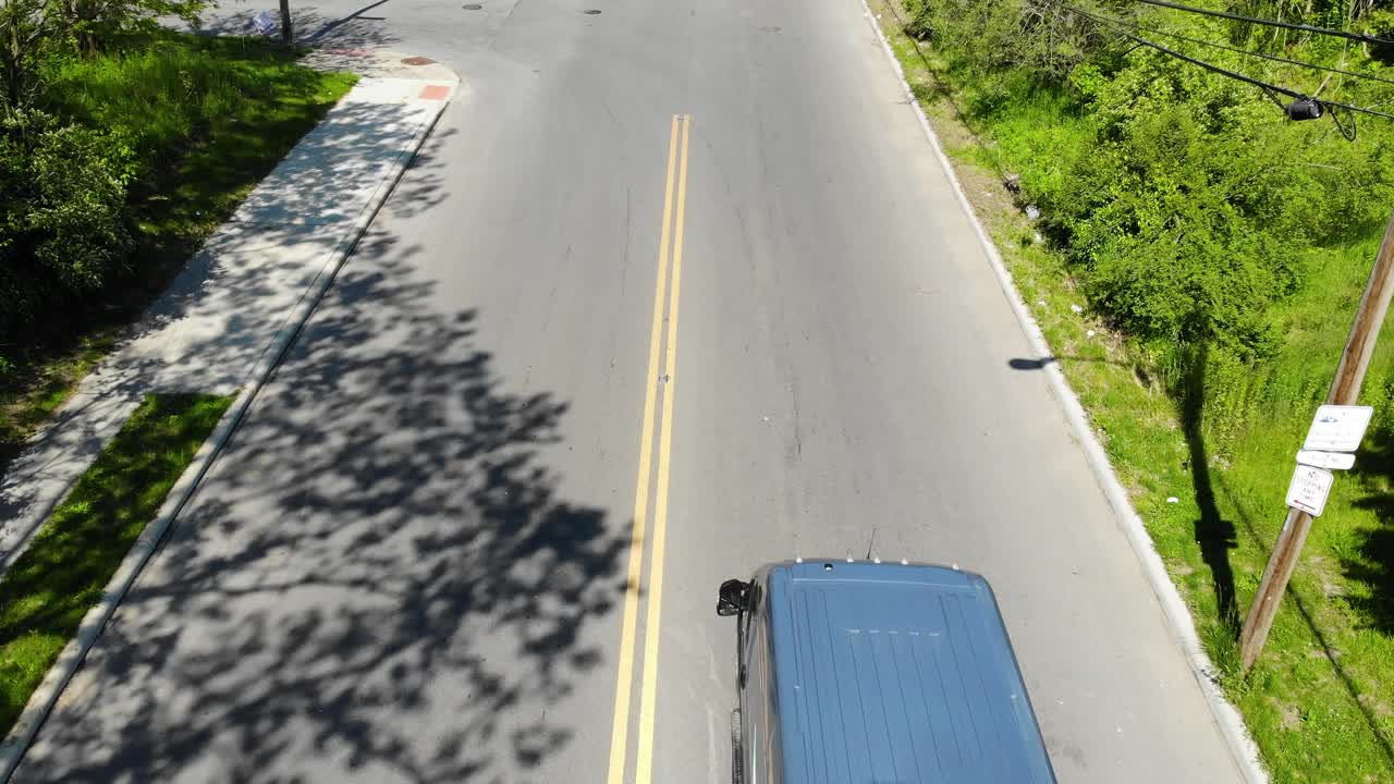 Amazon vans drive down a city street, aerial drone