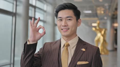 asian man in suit making ok gesture