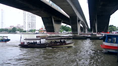 thai river boat passing under bridge in the centre of bangkok