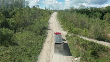 A-haulage-vehicle-drives-along-a-dusty-rural-road-on-a-sunny-day