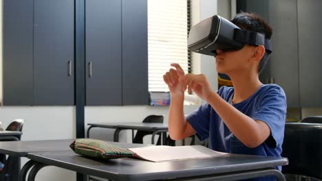 Vorderansicht-Eines-Asiatischen-Schuljungen,-Der-Am-Schreibtisch-Sitzt-Und-Virtual-Reality-Headset-Im-Klassenzimmer-4K-Verwendet