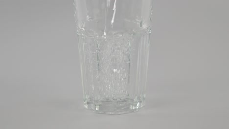 Stilles-Wasser-In-Zeitlupe,-Das-Vor-Neutralem-Hintergrund-In-Klares-Glas-Strömt