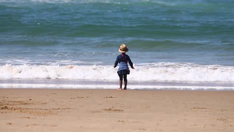 silhouette child girl washing hands in sea water golden hour sunrise evening summer