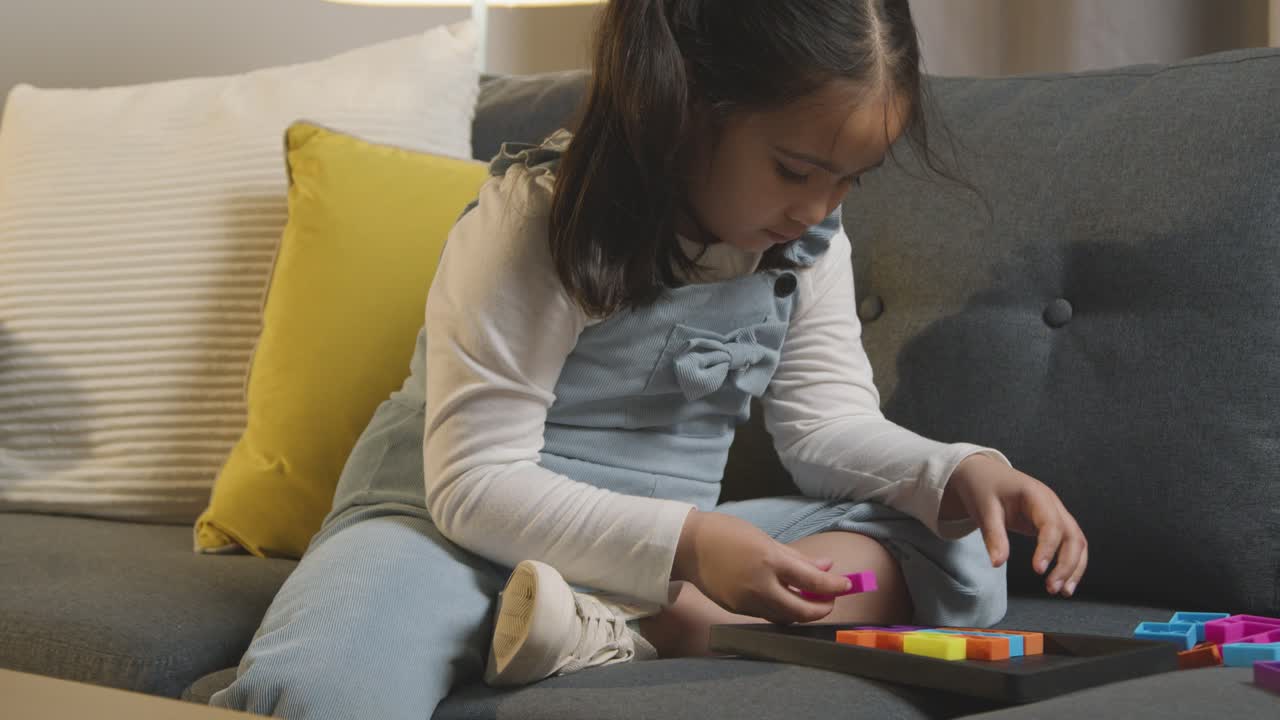 Young Girl On ASD Spectrum At Home Sitting On Sofa Solving Shape Puzzle 