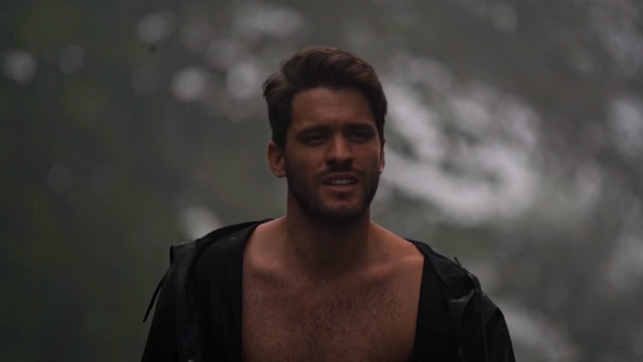 A man walks shirtless in the rain through a misty, green landscape in San Carlos, Costa Rica