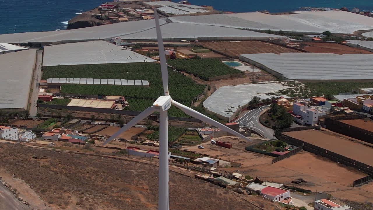 Aerial view zoom in to renewable power wind turbines rotating on coastal hilltop landscape