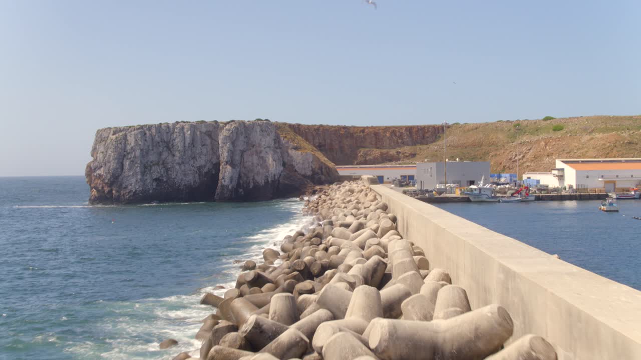 Frangiflutti del porto di Sagres con faro e onde, Algarve, Portogallo