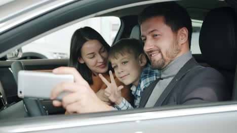 happy family taking a selfie in a new car