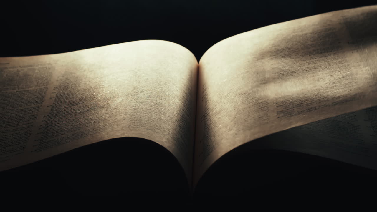 Drammatica svolta di pagina in un libro aperto e illuminato in una stanza buia.