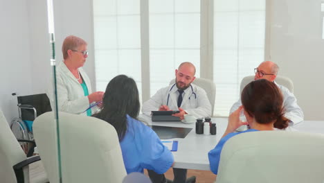 expert elderly woman doctor discussing with medical staff