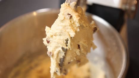 hand-held shot of a spatula removing scone mixture from a mixer tool