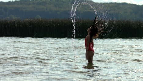 The-woman-splashes-the-water-with-her-wet-hair-submerged-in-the-lake-water