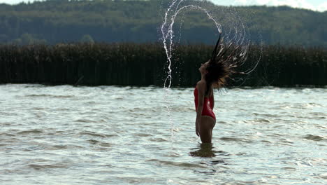 the woman splashes the water with her wet hair submerged in the lake water