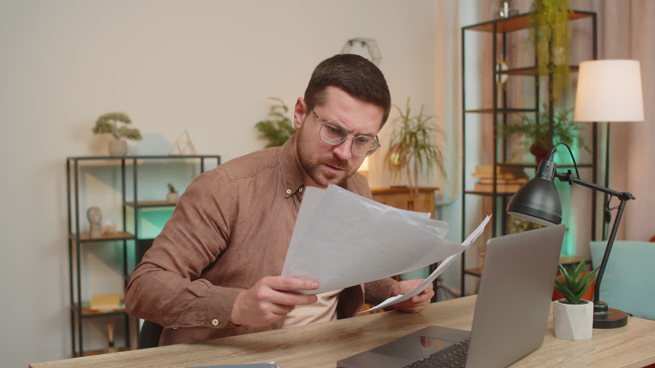 hombre de negocios estresado y molesto con una computadora portátil mirando facturas de deuda bancaria no pagadas sentado en el escritorio de la oficina en casa