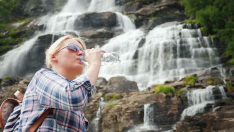 Junge-Frau-Trinkt-Wasser-Auf-Dem-Hintergrund-Des-Zwillingswasserfalls-Tvindefossen-In-Norwegen-Sauberes-Getränk