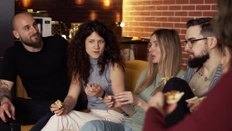 friends are sitting on the sofa - chatting, eating pizza