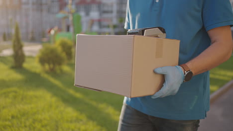 delivery hand of young man pays for purchases using the contactless payment nfs system. young delivery man hold package man client paying by phone for parcel transporting payment uniform express order