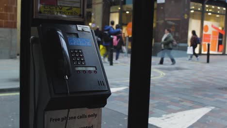 view from inside a black telephone box in london. united kingdom. peolple crossing the street in winter