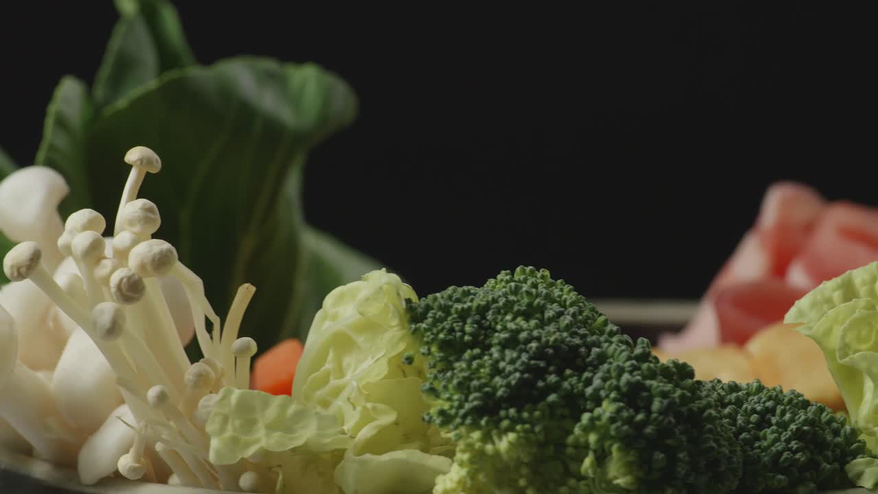 Close Up Of A Pot Of Shabu Ingredients Spinning Around On The Black Background