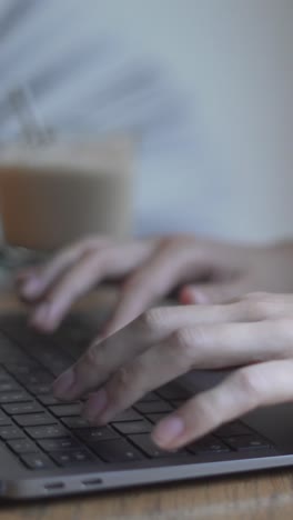 woman typing on a laptop at a cafe