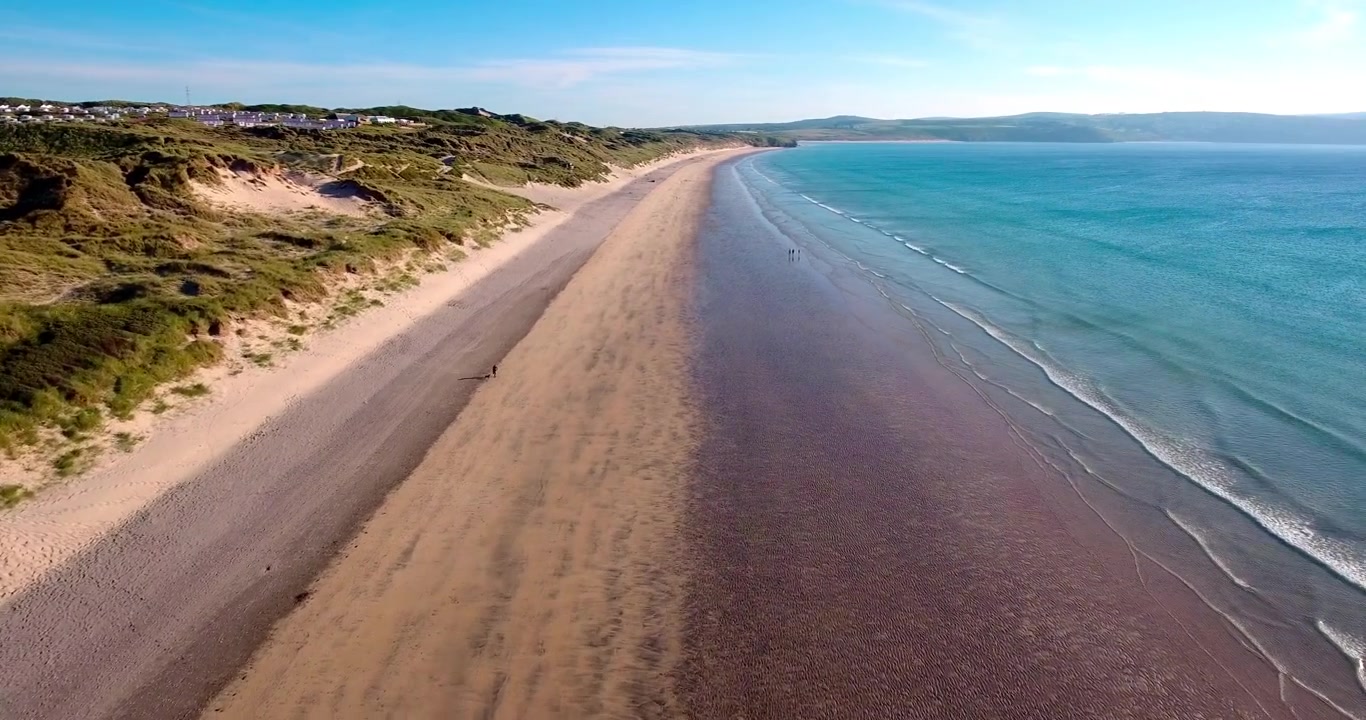 Ujęcie lotnicze 4K nad plażą Gwithian Towans w Kornwalii. Idealny letni wieczór, niesamowite słońce i krystalicznie czyste wody.