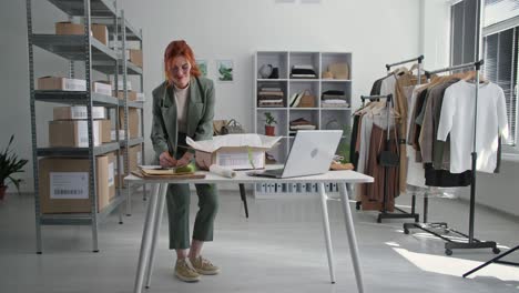 packing goods, woman small business owner packing goods for delivery to customers in online store checking orders on laptop at table in office warehouse