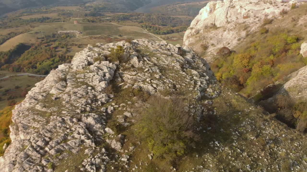 аэрофотосъемка разворота над скалистым холмом, на фоне долины и леса