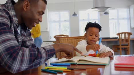 Vista-Lateral-De-Un-Padre-Negro-Ayudando-A-Su-Hijo-Con-La-Tarea-En-Una-Casa-Cómoda-4k