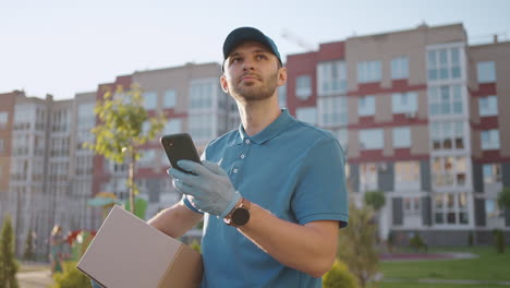 Male-courier-man-is-looking-for-mobile-phone-to-deliver-address-of-food-from-a-shop.-Delivery-guy-navigates-in-phone-in-city-searching-for-shop-delivery-addresses.-Fast-delivery