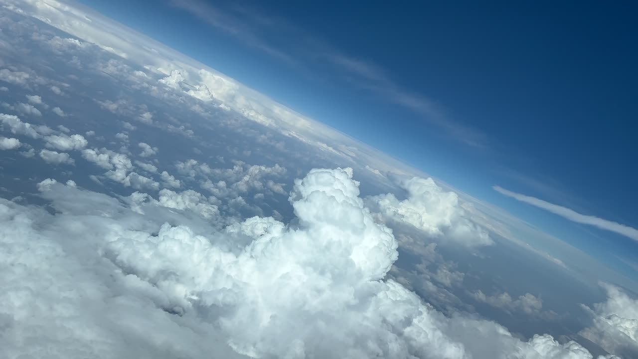 Vista aérea desde la cabina de un avión a reacción volando sobre un cielo azul con algunas nubes de tormenta al frente, girando a la izquierda para evitarlas. Metraje aéreo grabado desde la cabina. 4K 60FPS.