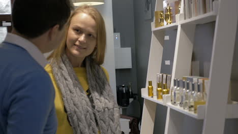 man and woman by the shelf with perfumery