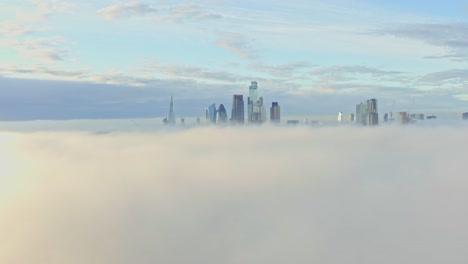 Toma-Aérea-De-Dolly-Back-Sobre-La-Niebla-De-La-Mañana-Hacia-El-Amanecer-De-Los-Rascacielos-Del-Centro-De-La-Ciudad-De-Londres