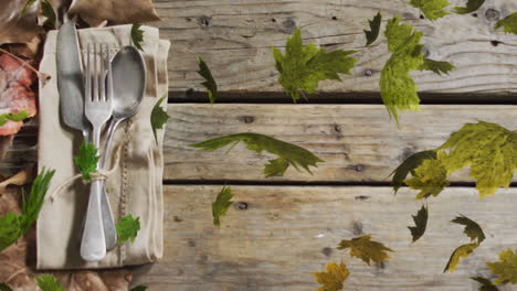 animation of leaves over cutlery and leaves on wooden background