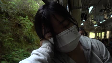 japanese girl wearing corona facemask sleeping on moving train