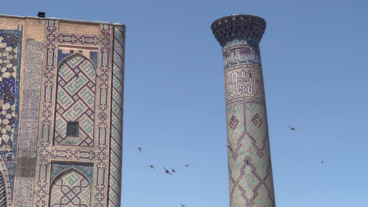 Birds circle Ulugh Bek Madrassah's minaret in Registan Square, Samarkand, Uzbekistan