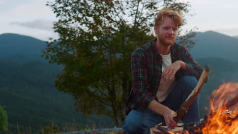 active traveler camp forest in mountains. close up hiker sit bonfire on nature.